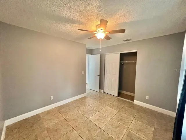 an empty room with closet and a chandelier fan