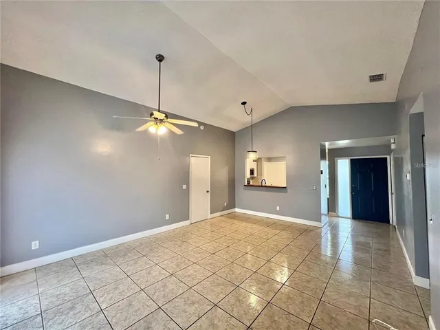 a view of an empty room with window and chandelier fan