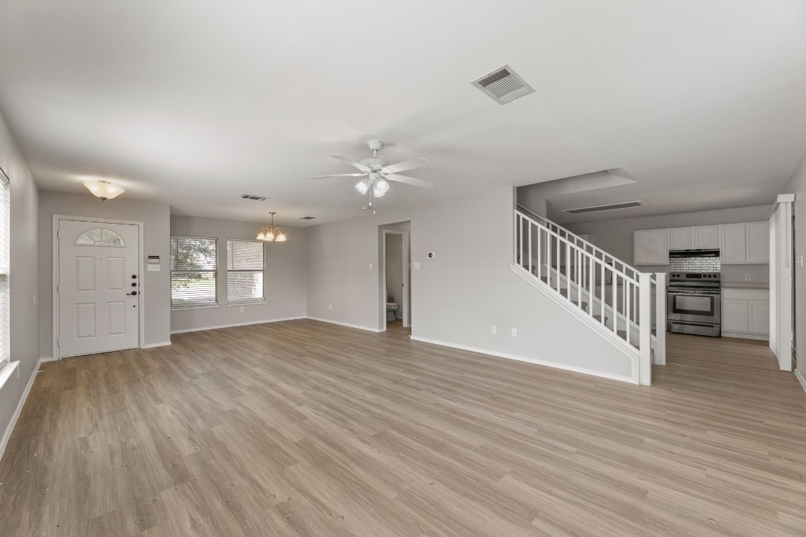 1308 Water Spaniel Way Round Rock, TX 78664 - Photo 4 of 25 a view of an empty room with wooden floor and a kitchen