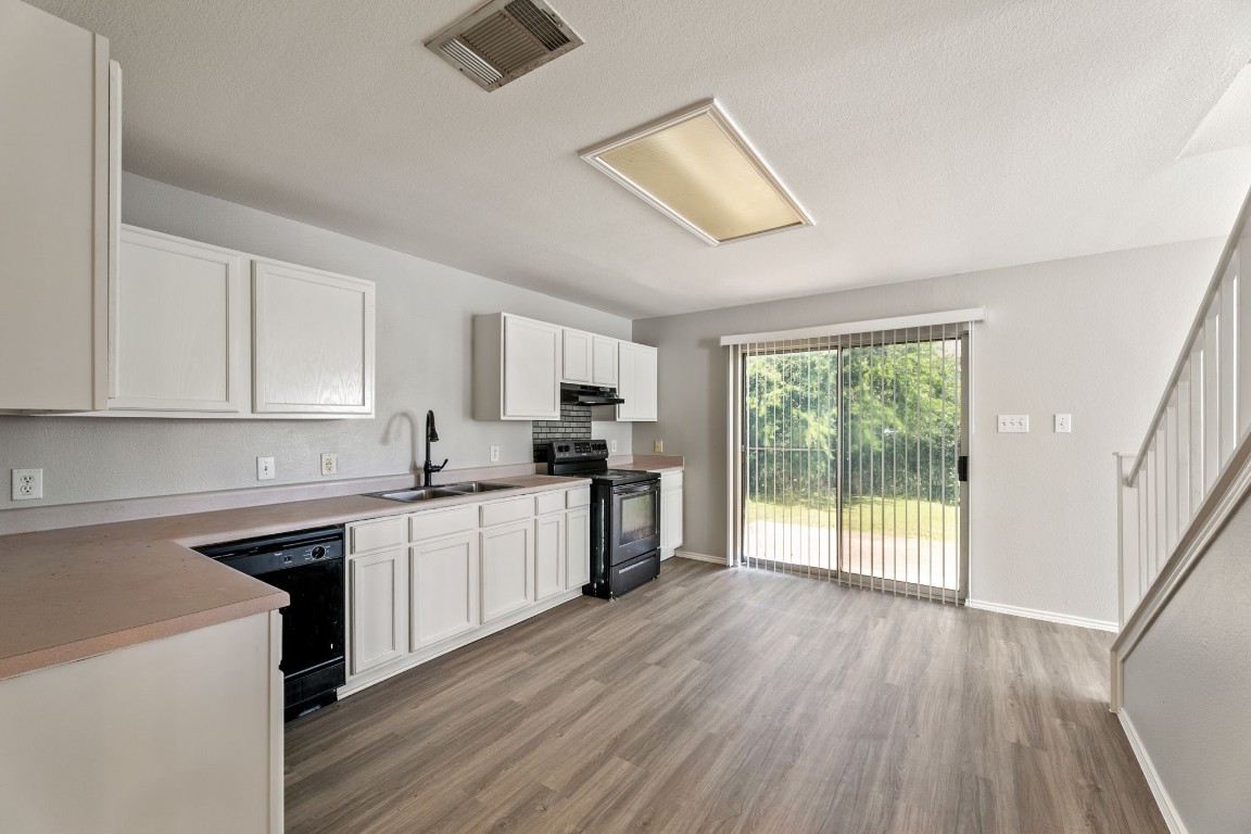 1308 Water Spaniel Way Round Rock, TX 78664 - Photo 7 of 25 a kitchen with wooden floors and white cabinets