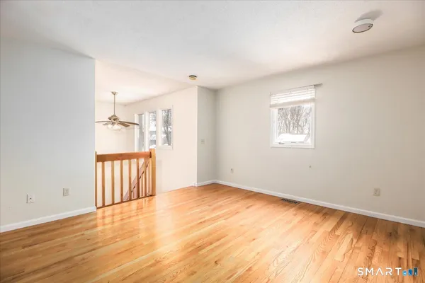 an empty room with wooden floor and windows