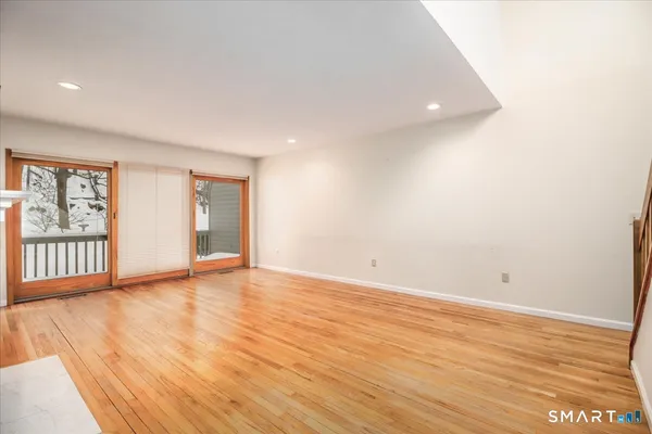 a view of an empty room with wooden floor and windows