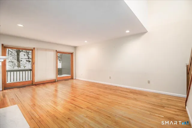 a view of an empty room with wooden floor and windows