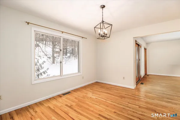 a view of empty room with wooden floor and window