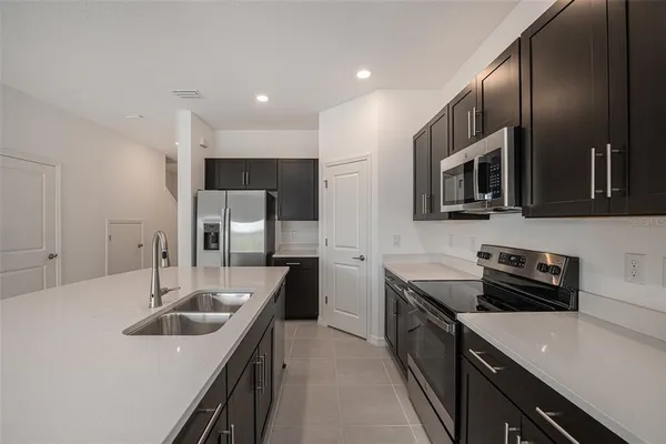 a kitchen with stainless steel appliances granite countertop a sink a stove and refrigerator