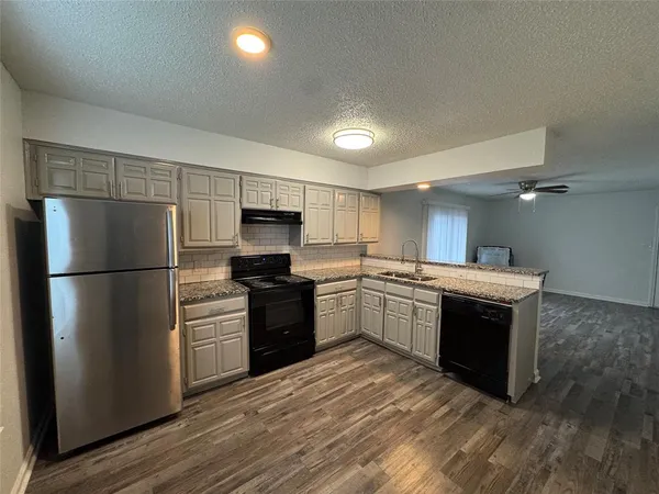 a kitchen with granite countertop a refrigerator and a stove top oven