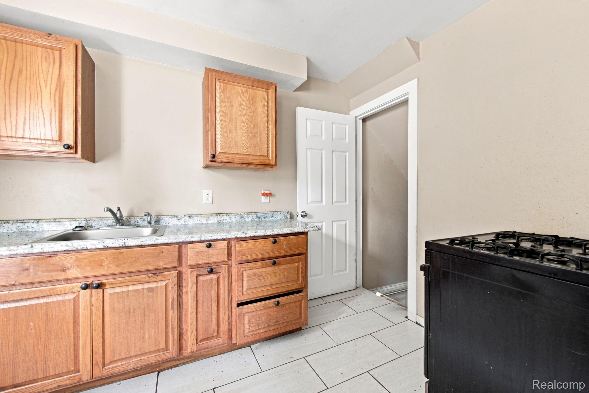 8882 Evergreen Road Detroit, MI 48228 - Photo 10 of 21 Wood-finish cabinetry with dark hardware, a stainless steel sink, and light-toned countertops