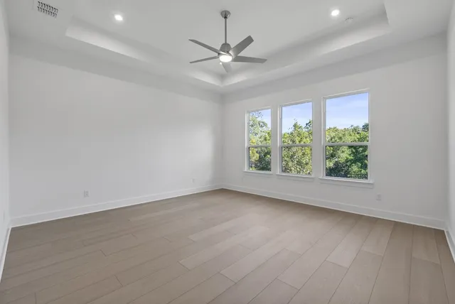an empty room with wooden floor window and ceiling fan