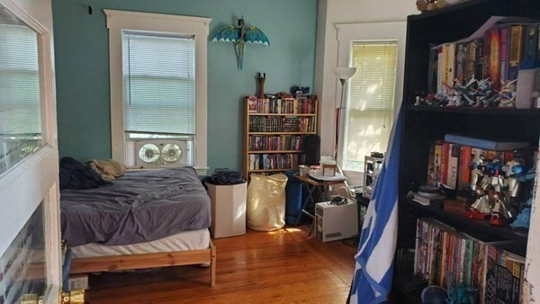 7-9 Reed Street Cambridge, MA 02140 - Photo 4 of 41 a bedroom with a bed and a bookshelf with wooden floor