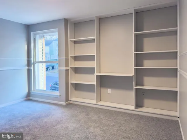 a view of an empty room with cabinet and a window
