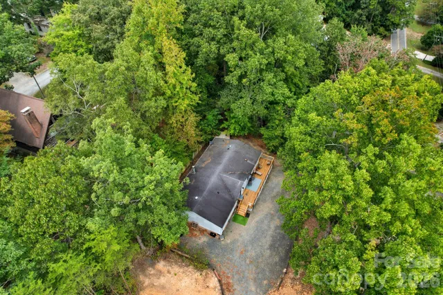 an aerial view of a house with a yard and covered with trees