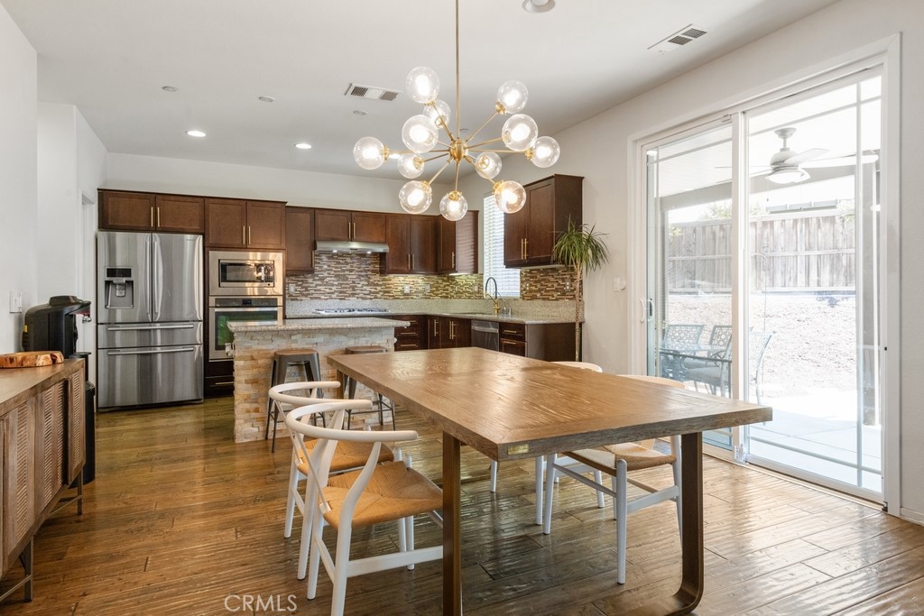 29463 Bouris Drive Menifee, CA 92584 - Photo 7 of 26 a kitchen with stainless steel appliances granite countertop a dining table chairs refrigerator and microwave