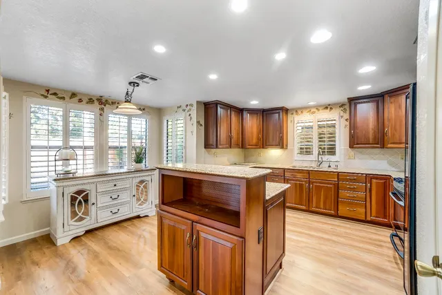 a large kitchen with kitchen island granite countertop a large window and white cabinets