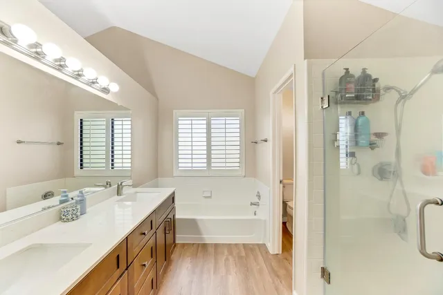 a bathroom with a tub double vanity sink and a mirror