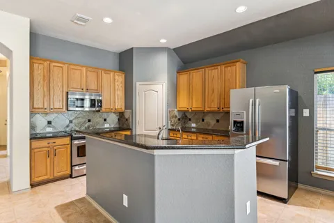 a kitchen with stainless steel appliances granite countertop a refrigerator a sink a stove and island