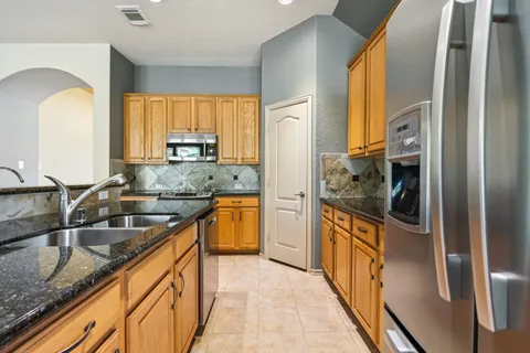 a kitchen with granite countertop a sink and a refrigerator
