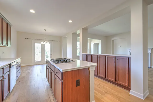 an empty room with wooden floor chandelier and windows