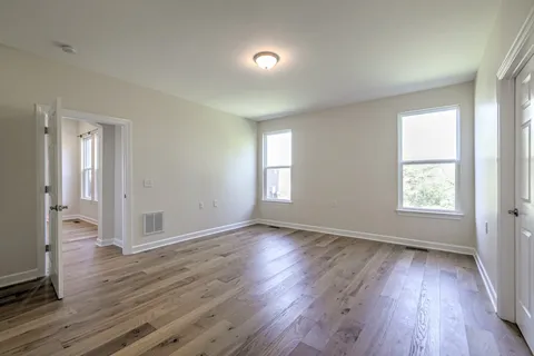 an empty room with wooden floor and windows