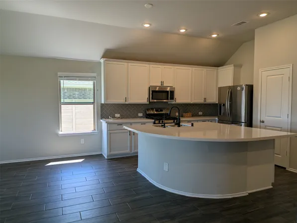 a kitchen with stainless steel appliances a refrigerator a stove a sink cabinets and a wooden floor