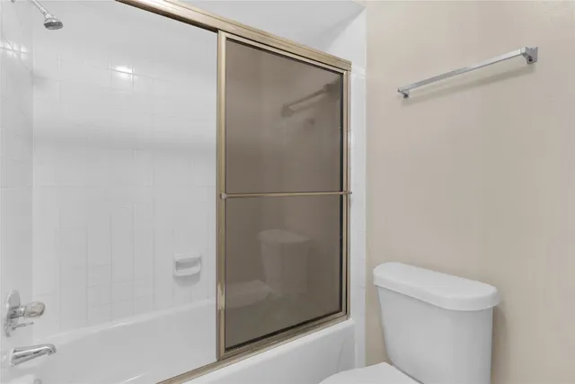 a white bath tub sitting next to a white toilet and vanity