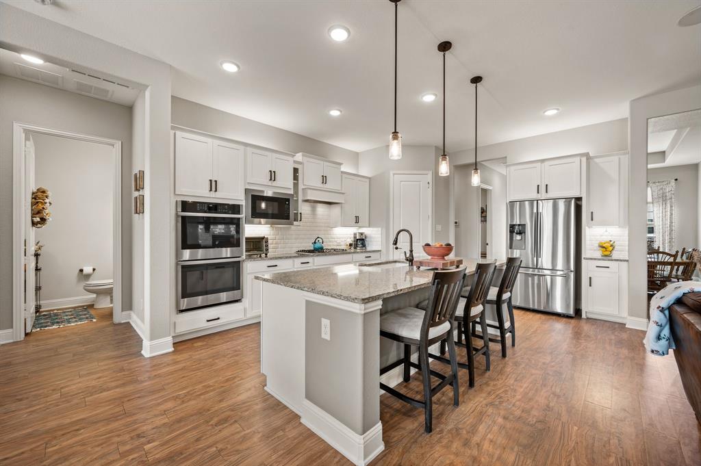 1226 Aster Place Haslet, TX 76052 - Photo 6 of 40 a kitchen with stainless steel appliances kitchen island granite countertop a table chairs and a refrigerator