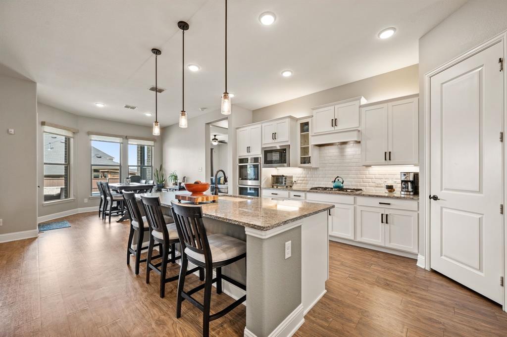 1226 Aster Place Haslet, TX 76052 - Photo 7 of 40 a kitchen with stainless steel appliances kitchen island granite countertop a table chairs sink and cabinets
