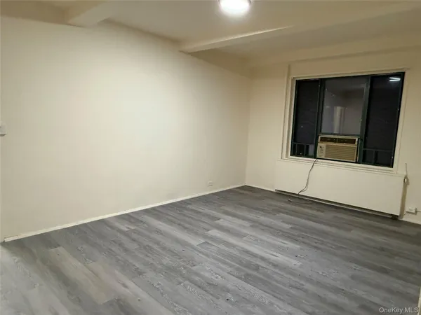 a view of an empty room with wooden floor and a sink