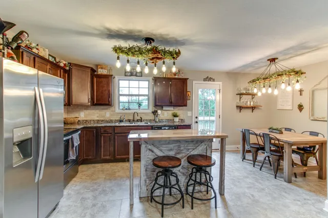 a kitchen with granite countertop a center island stainless steel appliances and a window