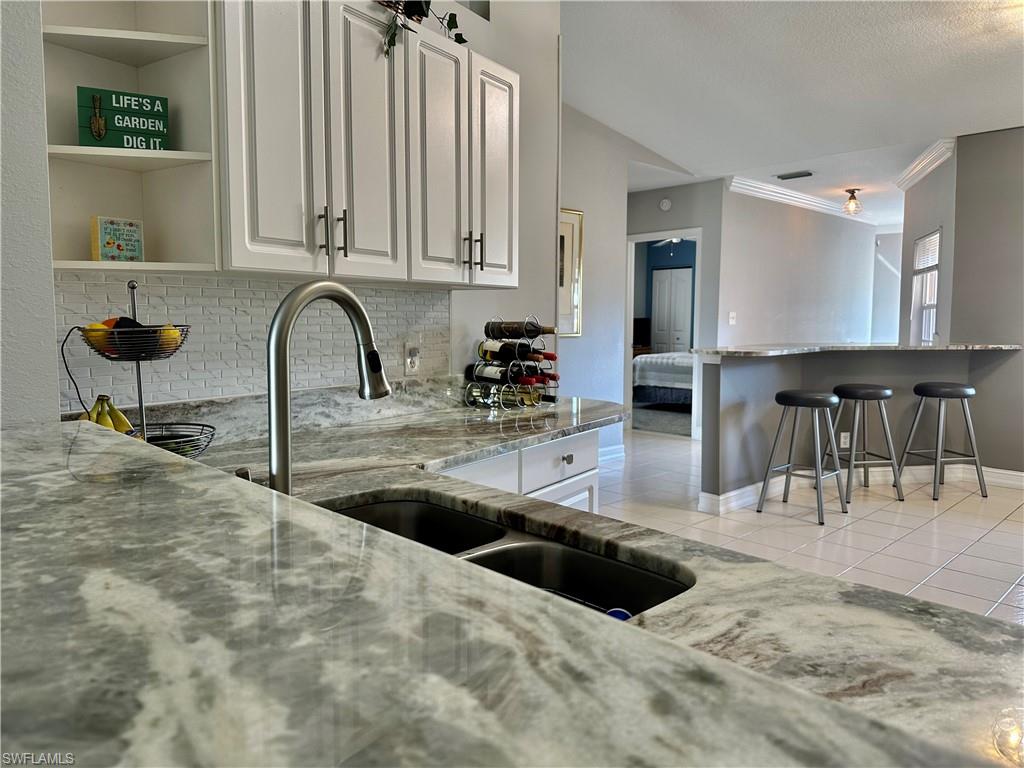 9165 Michael Circle, Unit 1002 Naples, FL 34113 - Photo 5 of 39 a view of a kitchen with kitchen island a sink and a large window