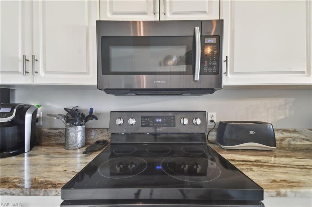 9165 Michael Circle, Unit 1002 Naples, FL 34113 - Photo 7 of 39 a kitchen with a stove and a white cabinet