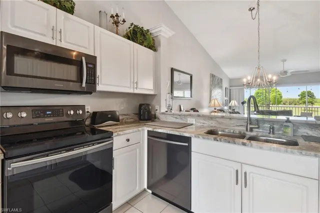a kitchen with stainless steel appliances granite countertop grey cabinets a stove a sink and a microwave