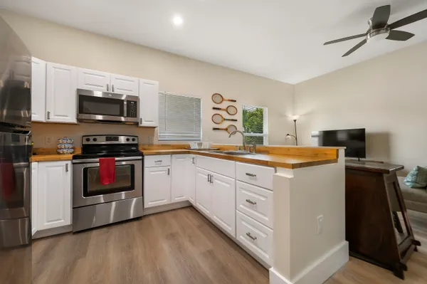 a kitchen with stainless steel appliances a stove top oven a sink a microwave and wooden cabinets