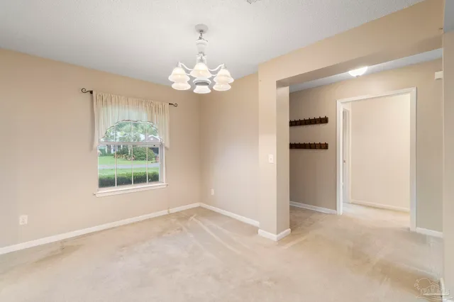 an empty room with chandelier fan and windows