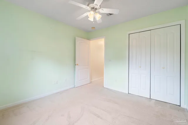an empty room with closet and a chandelier fan