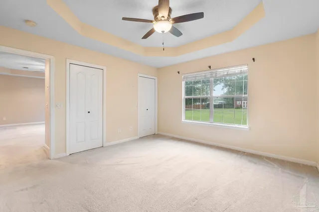 en empty room with windows and ceiling fan