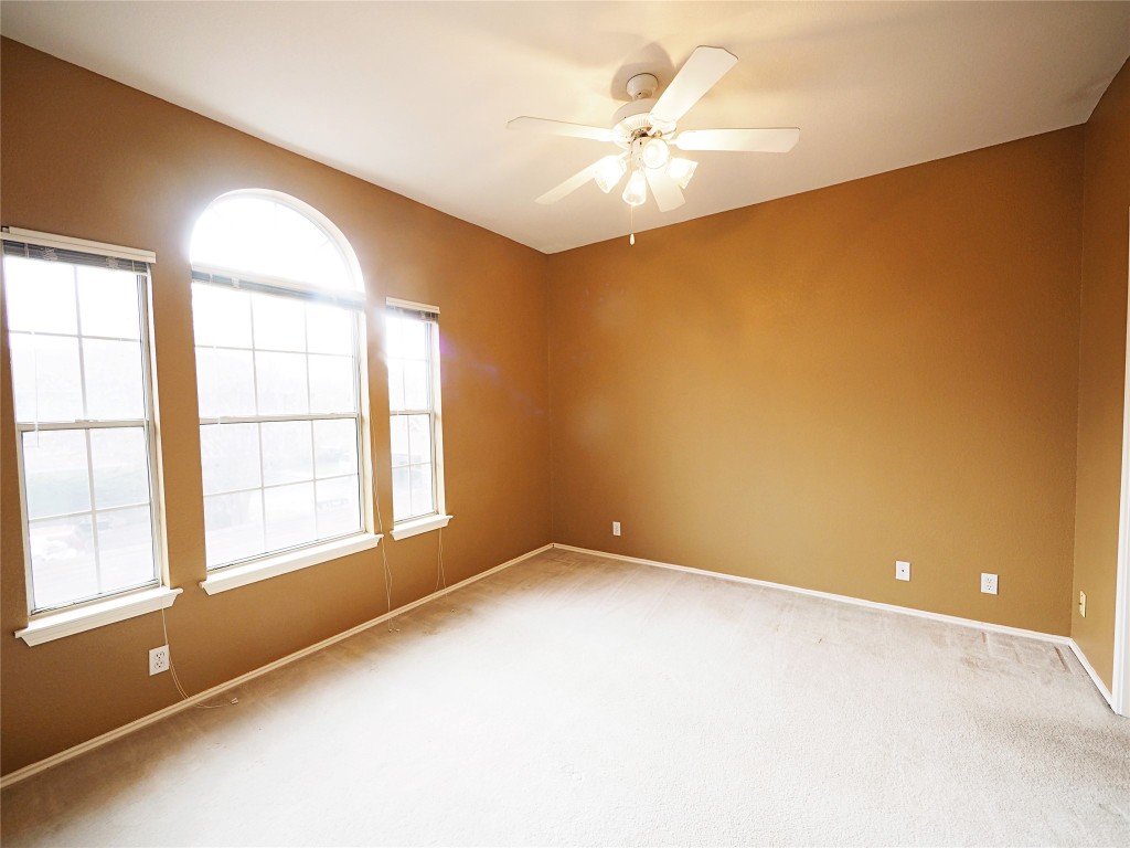 12401 Los Indios Trail, Unit 13 Austin, TX 78729 - Photo 13 of 27 an empty room with a chandelier fan and windows