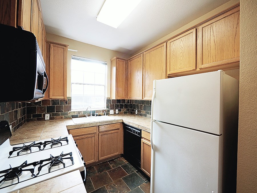 12401 Los Indios Trail, Unit 13 Austin, TX 78729 - Photo 21 of 27 a kitchen with a refrigerator a stove a sink and a window