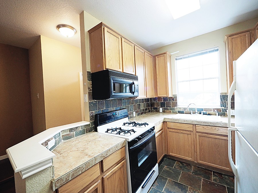 12401 Los Indios Trail, Unit 13 Austin, TX 78729 - Photo 22 of 27 a kitchen with a sink stove and microwave