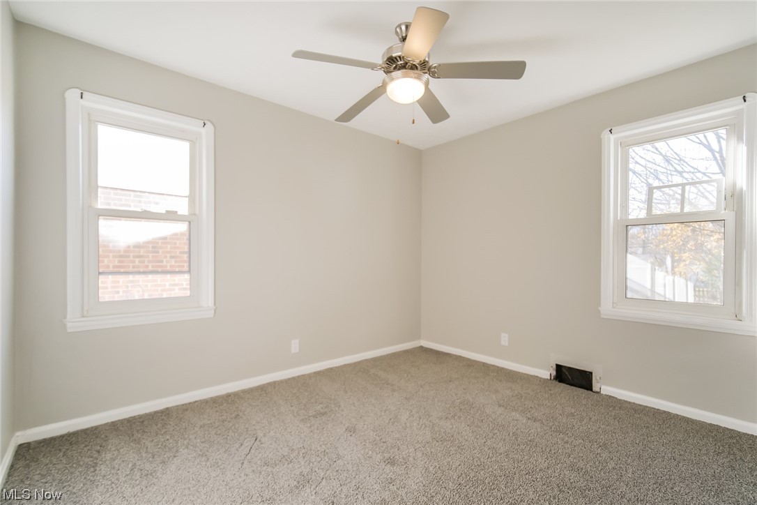 1668 Winchester Road Cleveland, OH 44124 - Photo 11 of 20 Empty room featuring light colored carpet, ceiling fan, and plenty of natural light