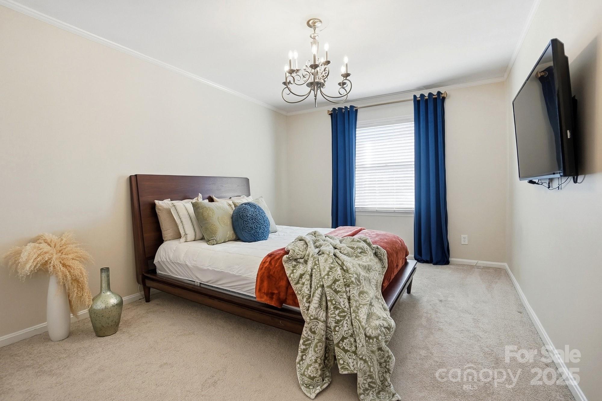 5913 Quail Hollow Road Charlotte, NC 28210 - Photo 41 of 47 a bed sitting in a bedroom next to a window with a flat screen tv and a chandelier
