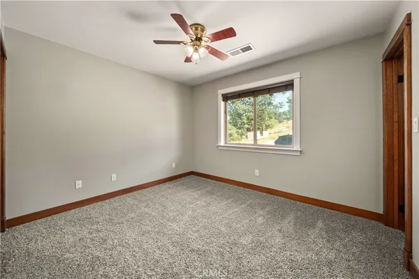 an empty room with windows and ceiling fan