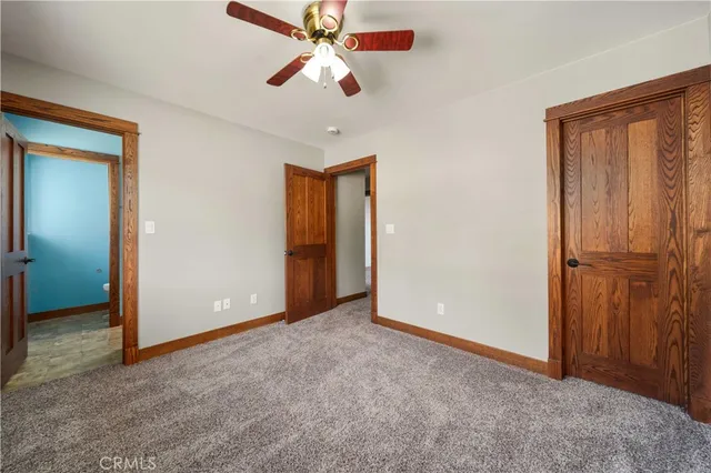 an empty room with closet and a chandelier fan