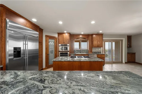a view of a kitchen with kitchen island granite countertop a refrigerator and a sink