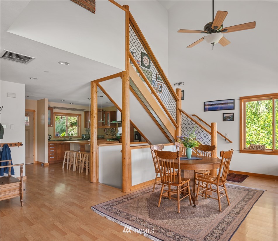 5909 Crescent Beach Road Northwest Vaughn, WA 98394 - Photo 13 of 35 a dining room with wooden floor a chandelier a wooden table and chairs