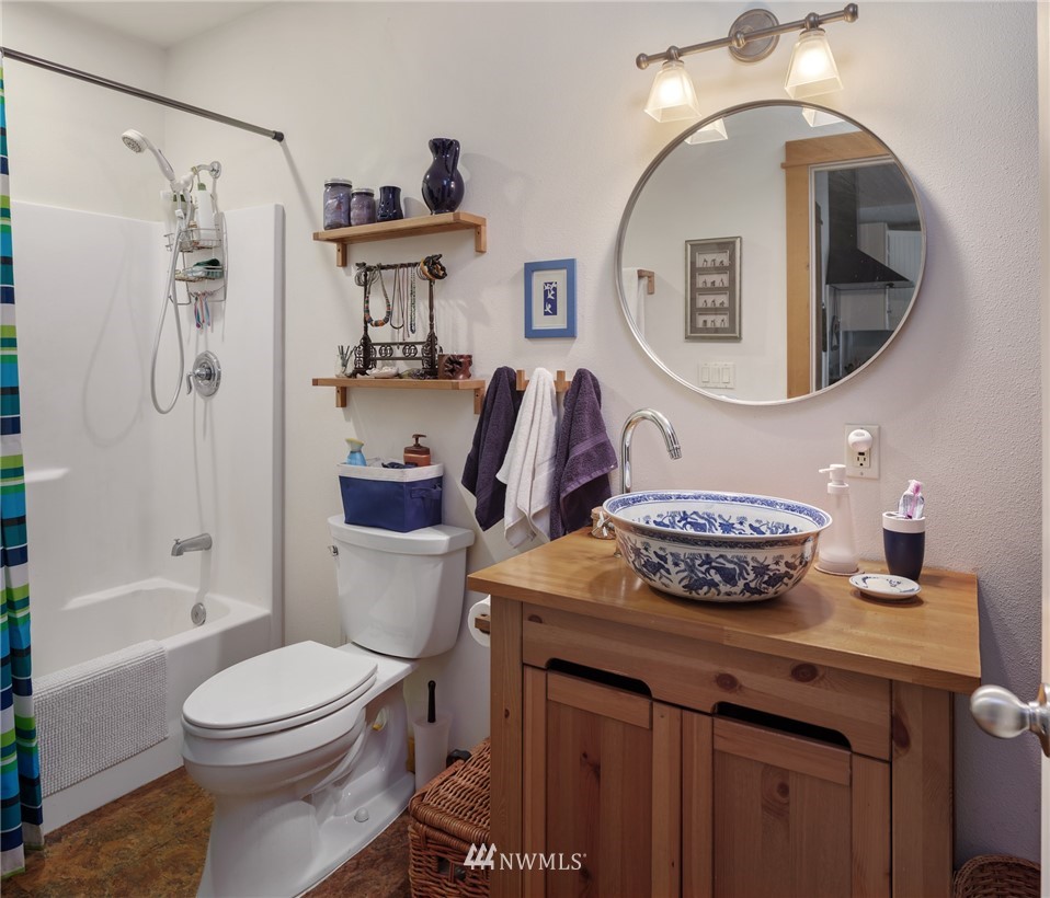 5909 Crescent Beach Road Northwest Vaughn, WA 98394 - Photo 26 of 35 a bathroom with a granite countertop toilet a sink and a mirror