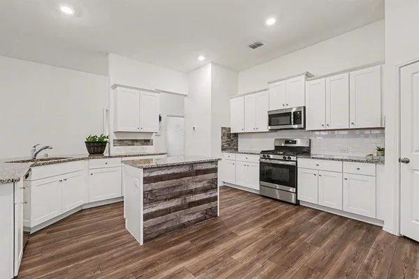 a kitchen with granite countertop white cabinets and stainless steel appliances