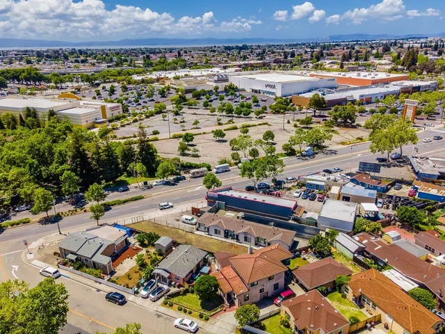 an aerial view of a city with lots of residential buildings and ocean view in back