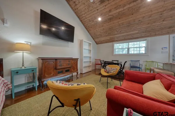 a kitchen with stainless steel appliances kitchen island granite countertop a refrigerator a oven a sink a dining table and chairs with wooden floor