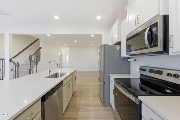 a kitchen with stainless steel appliances white cabinets white stove a microwave and a refrigerator