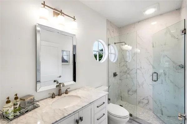 a bathroom with a granite countertop sink toilet a mirror and shower